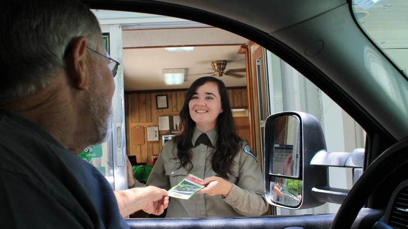 Park staff at ranger station giving visitor a brochure